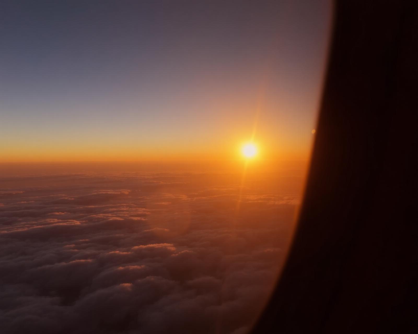 Sunset above the clouds from an airplane window